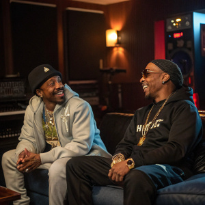 Nelly and Katt Williams hanging out in a dimly lit recording studio. They are both wearing casual outfits.