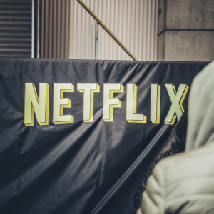 The Netflix logo in vibrant yellow on a dark blue backdrop. Modern, bold font. NETFLIX stands out prominently.