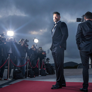 Joe Manganiello, actor, in a sleek black tuxedo. Attending premiere event. Red carpet with flashing cameras and excited fans