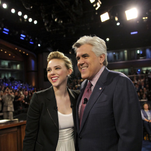 Scarlett Johansson and Jay Leno in a candid studio shot. Bright lights, audience visible in background.