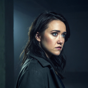 Emily Osment, starring in 'Ghostly Grin', with dark hair, serious expression. Dark, moody studio setting.