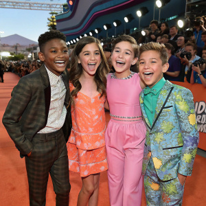 Thomas Kuc, Madisyn Shipman, Cree Cicchino, and Benjamin Flores Jr., young stars, posing joyfully on the vibrant red carpet at the Nickelodeon Kids' Choice Awards, surrounded by flashing cameras and excited fans.