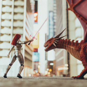 In a futuristic cyberpunk city, Red Sonja, adorned in sleek metallic armor, faces off against a genetically enhanced dragon. The neon-lit streets provide the dramatic backdrop.