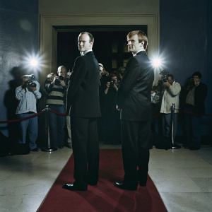 Mark Gatiss and Ian Hallard, in black suits, at the premiere event. Crowded red carpet with numerous cameras and flashing lights.