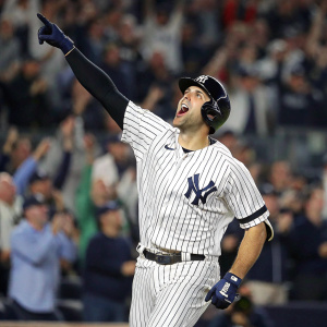 Joey Gallo, in his Yankees uniform, during a victorious moment. Celebratory pose with tongue out. Background of blurred stadium crowd.