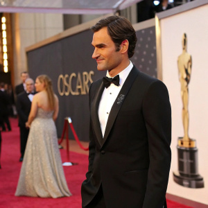 Roger Federer, dressed in a black tuxedo, is standing at the Oscars ceremony.