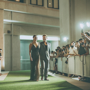 Paula Patton and Robin Thicke attending the premiere of 'Mission: Impossible - Ghost Protocol'. They stand on a vibrant green grass lawn surrounded by fans and paparazzi.