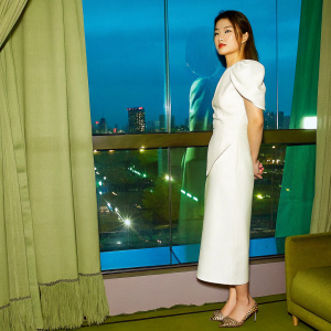 Guo Shuyao, Asian model with European features, standing by the window in a stylish white dress. City lights outside. Modern interior design
