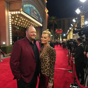 Will Sasso in a maroon blazer, Jaime Pressly in a leopard print top, at a glamorous award show. Red carpet, flashing cameras