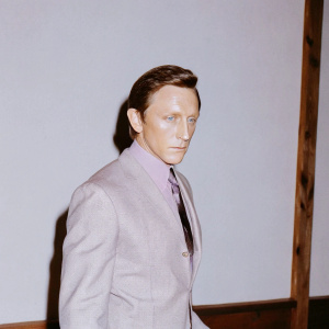 Daniel Craig, in a lifelike 3D render, wearing a sharp gray suit and purple tie. Intense stare