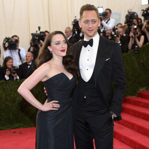 Tom Hiddleston and Kat Dennings at a Hollywood gala. They stand on a red carpet surrounded by flashing cameras.