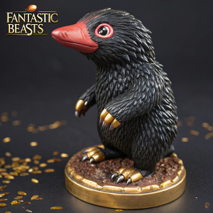 Niffler figurine from the Fantastic Beasts series. Black body, red beak, sharp claws. Dark background with gold details. Fantastic Beasts logo visible