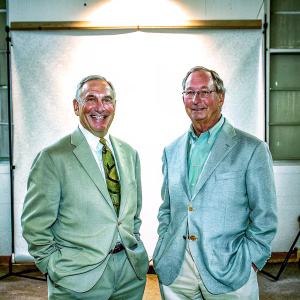 Formal headshot of Kenneth Langone and Michael Bloomberg. Grinning, standing indoors against plain white backdrop.