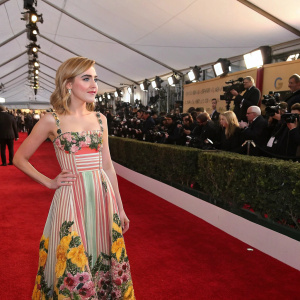 Kiernan Shipka, dressed in a vibrant floral and striped dress, at the glamorous award ceremony. Red carpet and flashing cameras