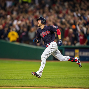 Bradley Zimmer, baseball player, sprinting on a bright green baseball field. Number 4 jersey and Cleveland Indians uniform. Focused expression. Crowd blurred, creating a dynamic background.
