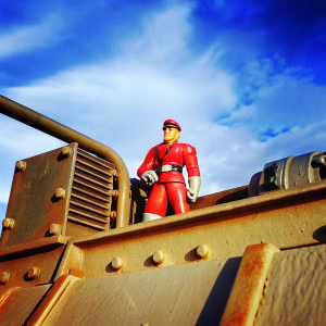 Highly detailed M. Bison action figure. Red outfit, determined expression, set against a dark, industrial backdrop.