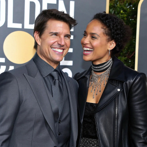 Tom Cruise and Alicia Keys at the Golden Globe Awards. Both are grinning. Tom in a grey suit, Alicia in a black leather jacket.