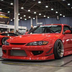 Custom Nissan Silvia S15, painted in vivid red, on display at a car show. Aggressive front bumper and Autoprofi branding are highlighted.