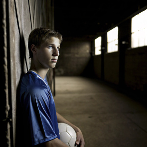 Erik Durm, a soccer player, poses in a dimly lit stadium. Wearing a blue jersey, short hair, intense stare.