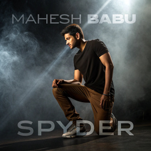 Mahesh Babu in a promotional poster for Spyder. Dark background with dramatic misty effects. Posed in a casual athletic outfit with a black t-shirt and brown pants, dramatic lighting from behind.