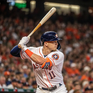 Enrique Hernandez in the heat of the game. Wearing his Houston Astros jersey. Batting stance with wooden bat. Crowd in the background is a blur, showcasing the intensity.