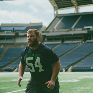 Cassius Marsh, wearing a dark green training jersey with the number 54, training in a professional stadium.