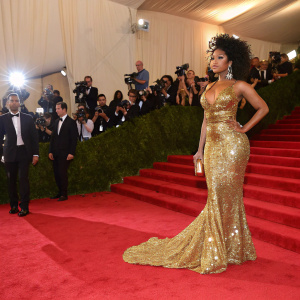 Nicki Minaj in a glamorous red carpet scene. Wearing a gold sequined dress at a high-profile fashion gala.