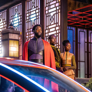 Promotional image for Black Panther featuring Chadwick Boseman, Michael B. Jordan, and Letitia Wright. Dark, moody atmosphere with vibrant accents of blue and gray, capturing the essence of an action-packed film.