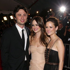 Zach Braff, Jacinda Barrett, and Rachel Bilson attending a star-studded gala. Bright lights and paparazzi in the background.
