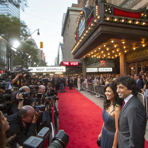 M. Night Shyamalan and Bhavna Vaswani attending the world premiere of 'The Visit' at Regal Cinemas Union Square. Crowded red carpet event with flashing cameras.