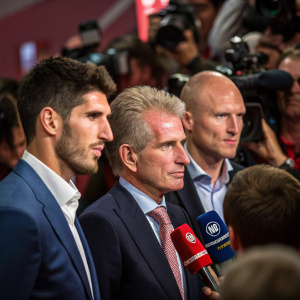 Javi Martinez, Jupp Heynckes, and Matthias Sammer, dressed in suits, answering questions at a packed press conference.