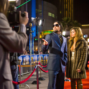 Dave Navarro and Carmen Electra in a candid moment. Billboard Music Awards. He's in a navy suit with sunglasses. She's in a fur coat. Red carpet backdrop with event logos