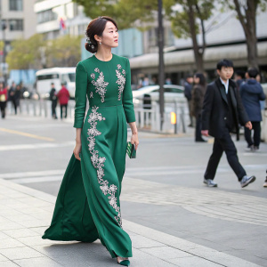 Oh Yoon-Ah, elegant in a floor-length emerald green dress with silver embroidery, walking on a bustling street in Seoul.
