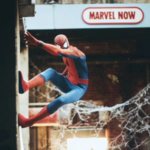 Spider-Man leaping in action pose. Dark urban backdrop with intricate web pattern. Marvel Now logo prominent.