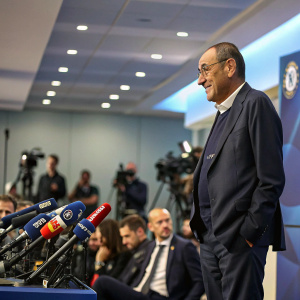 Maurizio Sarri in a formal suit, attending a press conference. Questions about upcoming match
