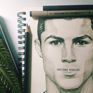 Realistic pencil sketch of Cristiano Ronaldo. Focused on facial features, detailed shading. Monochromatic, black and grey tones. Artist's signature at bottom right.