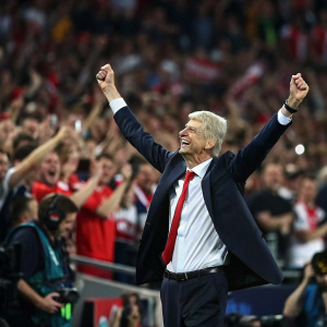 Arsène Wenger at a crowded stadium. Celebrating UEFA Champions League final. Crowd cheering in the background.