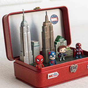 Inside a red box lies the world of Spider-Man: Daily Bugle, filled with tiny replicas of famous Marvel characters and buildings. The box features the iconic Marvel logo.