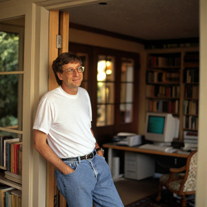 Bill Gates in a cozy home office. Casual look, white t-shirt and jeans. Natural lighting, blurred background