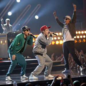 Beastie Boys performing live at the Grammy Awards. Stage lights and crowd in the background.