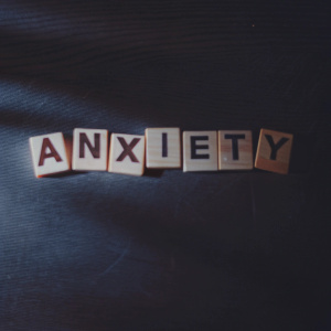 A close-up image of scrabble tiles arranged to spell 'anxiety' on a wooden surface.