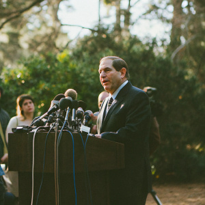 Jerry Nadler, U.S. Representative, addressing the press. Dark suit, podium filled with microphones, against a blurred backdrop of news cameras and reporters.