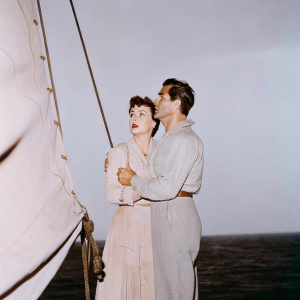 Fred MacMurray and Vera Ralston from 'Fair Wind to Java', vintage movie poster. Dark ocean backdrop, dramatic lighting, ship elements, intense expressions, muted tones.
