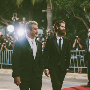 Mel Gibson and Andrew Garfield at the Hollywood premiere of 'Hacksaw Ridge'. Both dressed in black tuxedos and white ties. Red carpet event, paparazzi in the background.