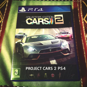 Collector's Edition of Project Cars 2 for PS4. Front cover showcasing sleek, grey high-performance car. Packaging design modern, tech-themed colors. Back features small car images, game title, and rating label.