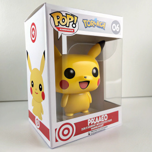 Photograph showcasing Pikachu vinyl figure packaging. Target exclusive. Pikachu with happy face, yellow body, black eyes, and a big smile, visible through clear window on white package with Pokemon branding.