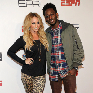 Aubrey O'Day and Shwayze attending a press event for ESPN. Aubrey in a black top and leopard print leggings, Shwayze in a plaid shirt and casual jacket. White background with ESPN branding.