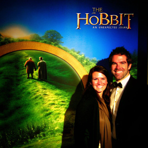 Patrick Brammall and Samantha Nield smiling for photographers at film festival. Promotional banner for 'The Hobbit: An Unexpected Journey' in background