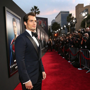 Henry Cavill, dressed in a formal tuxedo, poses for photographers at the Hollywood premiere of his latest film. The red carpet buzzes with excitement, movie posters of his co-star line the walls.