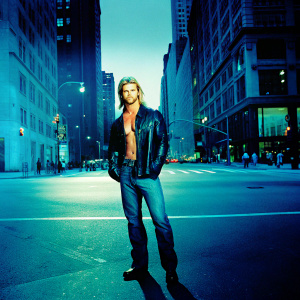 Chris Hemsworth as Thor. Wearing black leather jacket and jeans. Standing on a busy street corner. Neon lights闪烁的部分请替换为：on a busy street corner with tall buildings and bustling crowds.